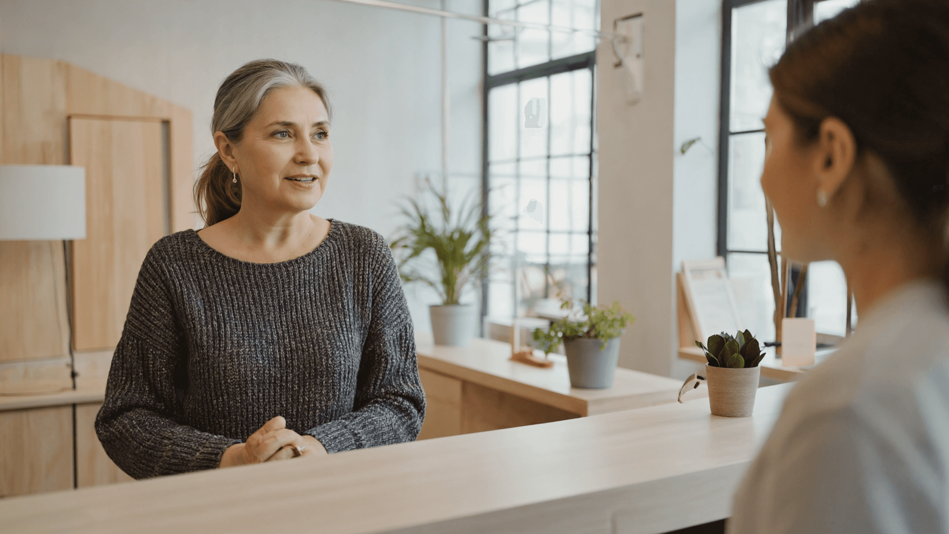 The owner of a small independent wellness studio talking with a customer at her reception counter